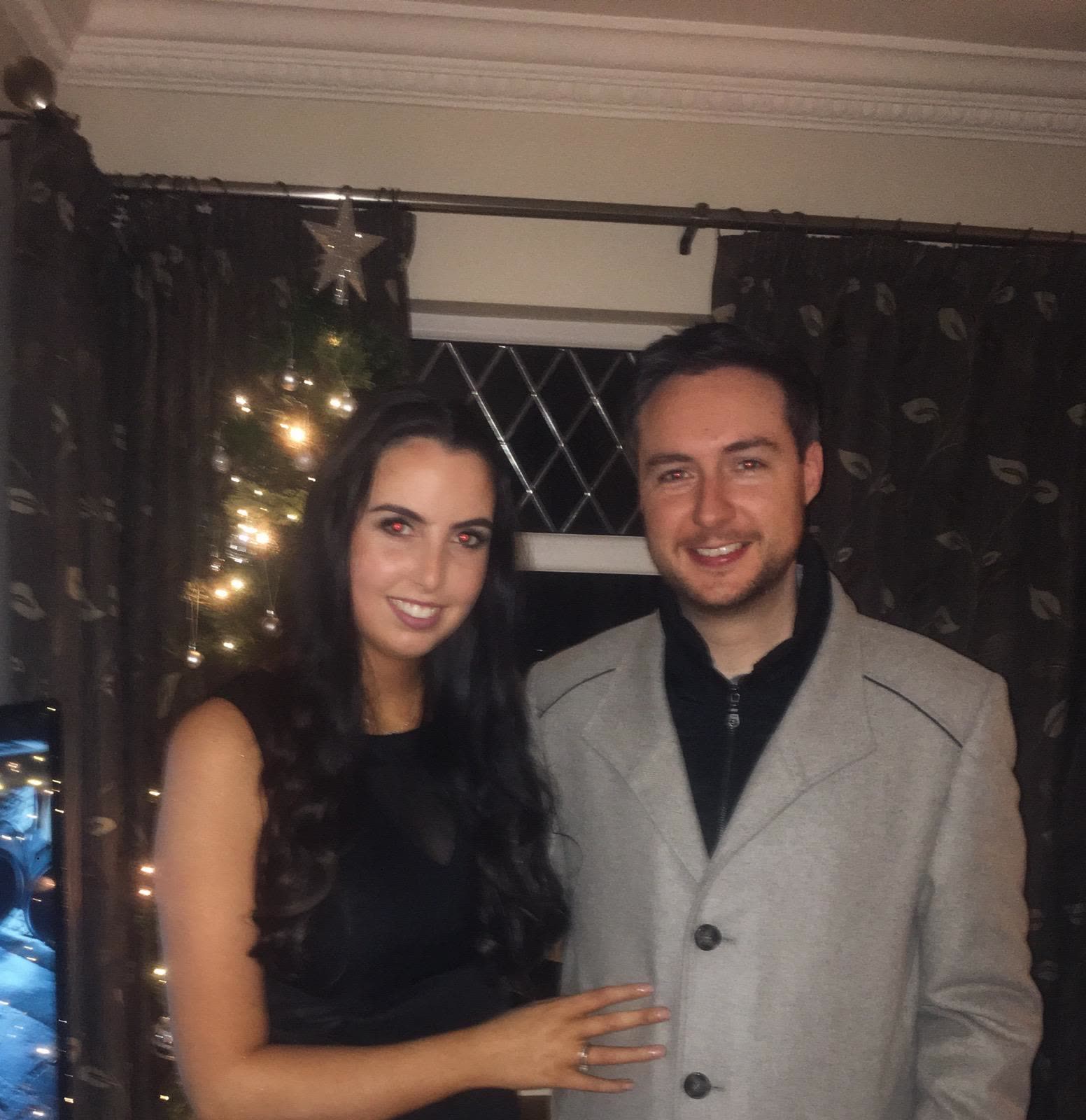 Showing off the engagement ring in front of the Christmas tree