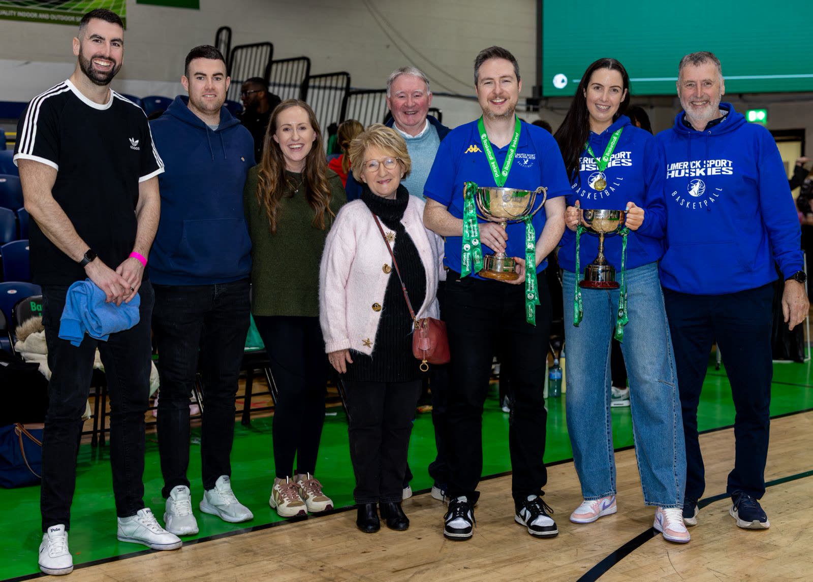 The wider family group on court with the trophies