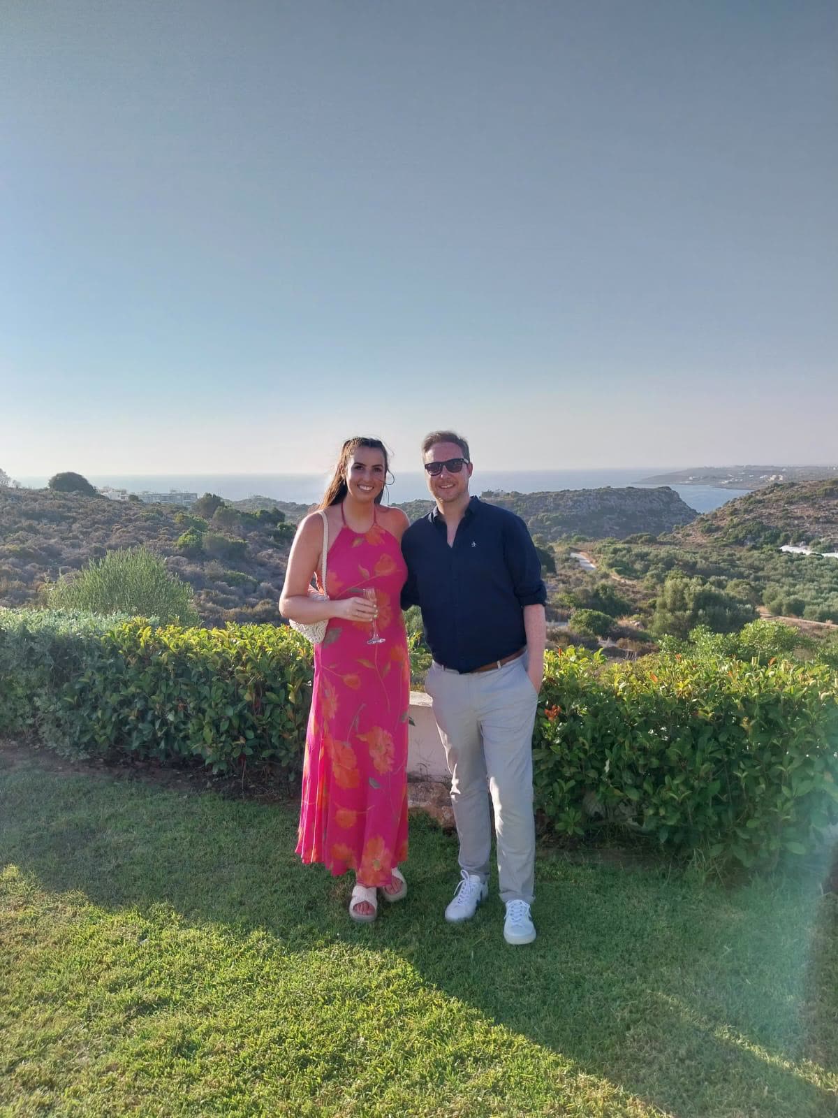 On a Greek hillside in a pink dress, sea behind