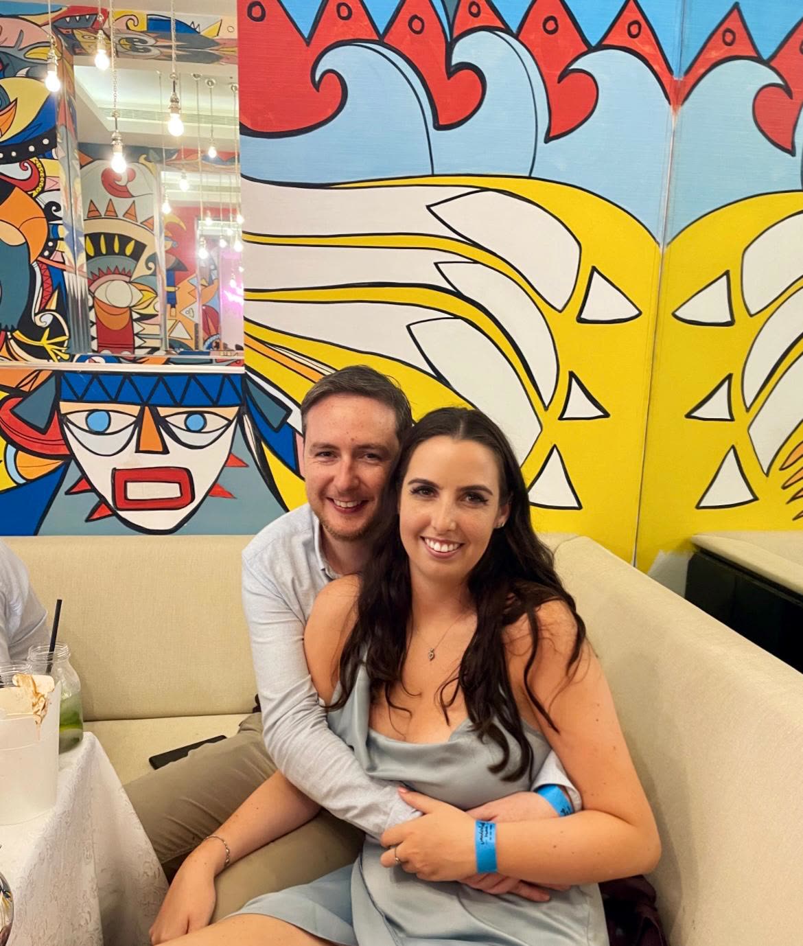 The pair cuddled into a booth in front of a bright painted mural